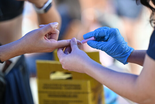 Nurse pricking a patient's finger to perform a blood glucose test.