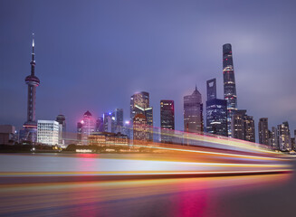 Obraz premium Shanghai colorful skyline with motion speed light of passing ferry in the foreground at night - Shanghai, China
