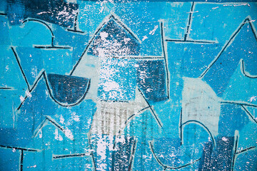 Abstract blue background of a worn wall with abstract black line drawings. © elenarostunova