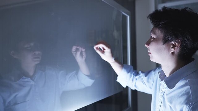 Focused man in business attire interacts with a glowing blue holographic brain diagram on a transparent touchscreen, symbolizing AI, digital intelligence, or neural networks.