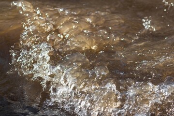 Dynamic spring brook water, churning with foamy cascades and sparkling droplets, reflecting the revitalizing power of nature. A cool, energetic flow captivates the eye. © PhotoChur