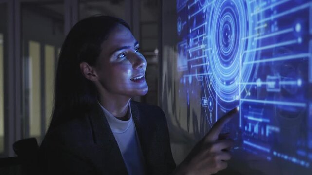 A professional man interacts with a high-tech circular data interface on a large digital screen, featuring graphs and data elements in a glowing blue theme.