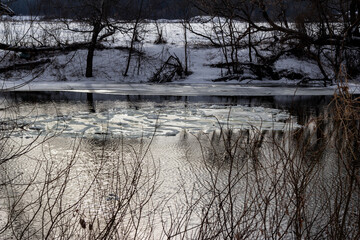 Drifting ice floes signal early spring's thaw on a tranquil river. The serene landscape awakens from winter's slumber, reflecting cold beauty © PhotoChur