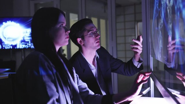 A professional man interacts with a high-tech circular data interface on a large digital screen, featuring graphs and data elements in a glowing blue theme.