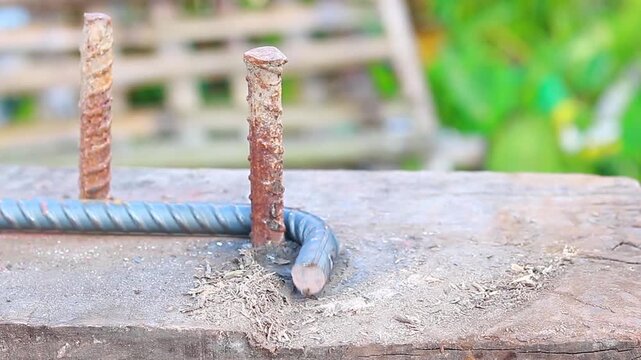 Close-up of a construction worker bending a steel rod using a manual rod bending tool