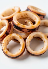 Naklejka premium Freshly prepared calamari rings are arranged in a pile on a clean white surface.