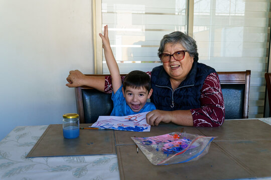 A boy joyfully raises his hand in celebration after finishing his painting. This gesture captures the playful energy and positive reinforcement of family learning.