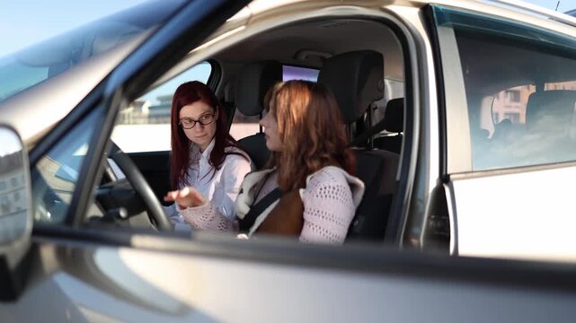  Driving instructor checks student knowledge as she explains how to start moving in car points controls and describes actions practical driving lesson inside vehicle