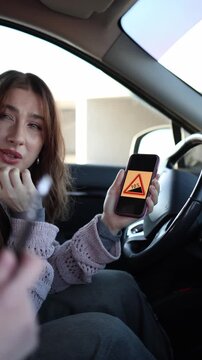 Vertical screen young woman driver checks road sign on phone during lesson while instructor explains meaning helping her understand traffic rules and improve driving knowledge