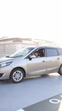 Vertical screen young woman driving car during practical driving lesson with instructor sitting beside learning road skills focusing on traffic and gaining confidence behind the wheel