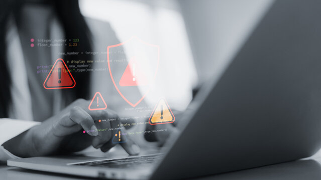 Cyber security alert with red warning icons on laptop screen.Hacker attack and data breach concept in modern office.System error and software vulnerability notification interface.Technology background