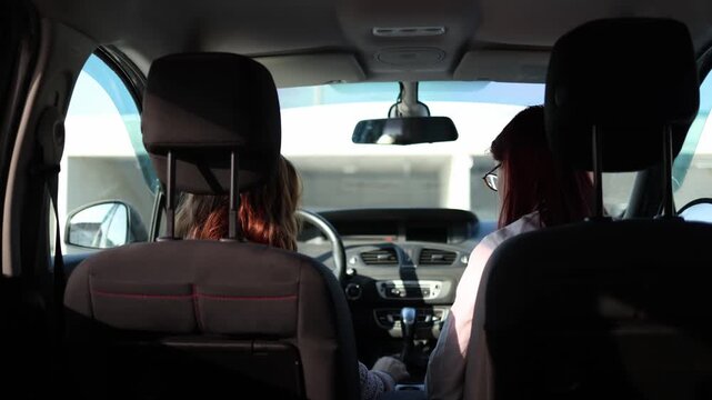 Driving instructor stops student before starting car points to seatbelt reminding safety rule as learner prepares to drive correcting mistake during practical lesson inside vehicle