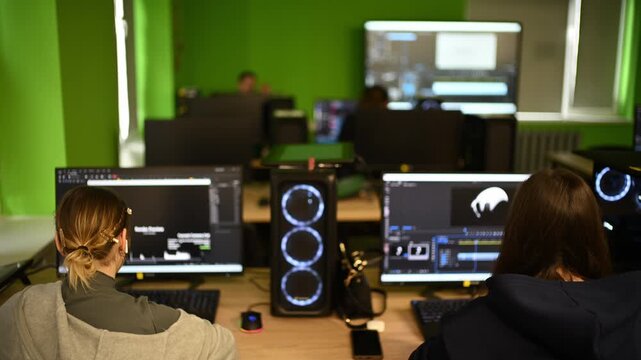 Modern computer classroom with multiple workstations, screens and students working