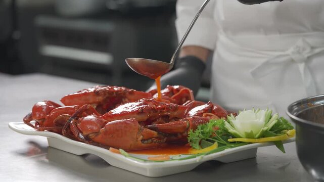 Close-up of chef cooking fresh mud crab in a professional kitchen with savory sauce.