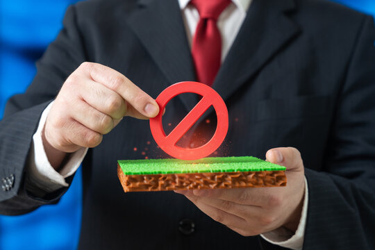 An official holds a no entry sign over a plot of land. Construction permits and restrictions apply. Protected areas and regulations limit development and preserve natural resources.