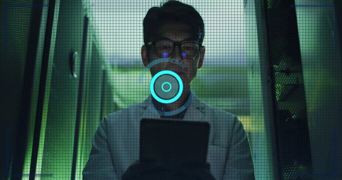 Standing Korean tech in white labcoat and glasses scanning data center server racks with tablet HUD