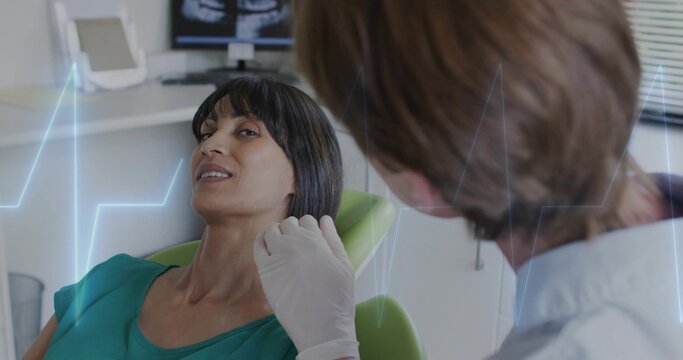 Checking doctor wearing gloves touching jaw of teal-top patient reclined green chair in clinic xray