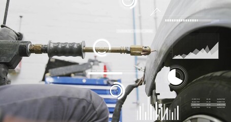 Kneeling tech wearing coveralls fixing fender in bay, holding stud welder with brass tip, hose, HUD