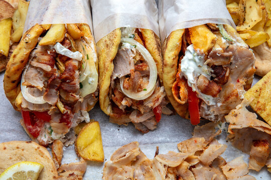 Gyros doner shawarma wraps stuffed with roasted meat, onions, tomato and tzatziki, closeup