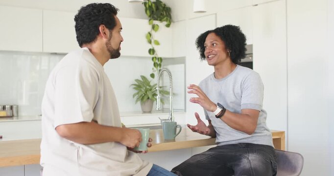 Holding mugs, two men catching up at kitchen island, right man gesturing emphatically