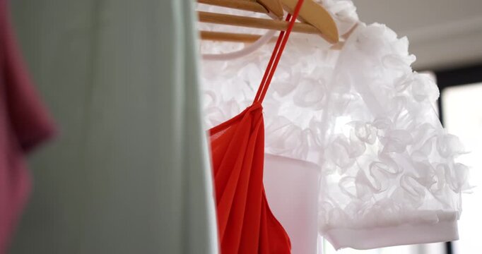 Lens is shifting right, sharpening focus to reveal red dress pleats beside white ruffle near window