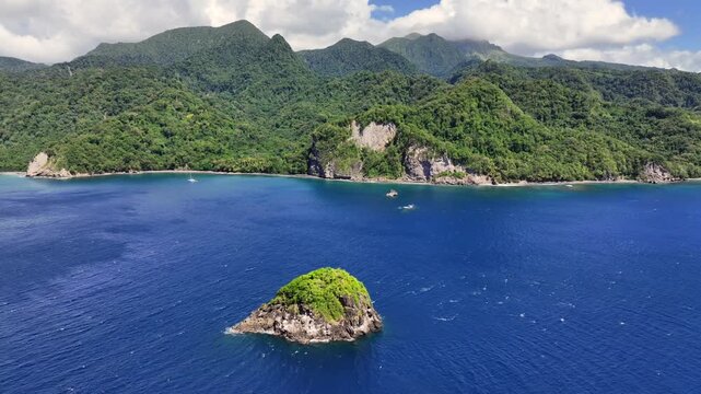 overflying "Rocher de la Perle" a small island towards Le Pr&ecirc;cheur coastline in Martinique, with famous Anse Couleuvre Beach and green hilly landscape - 4k aerial video footage 