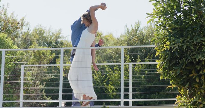 Couple meeting opposite sides by cable railing, playing, man in suit twirling woman in dress