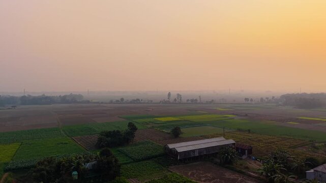 Aerial view of a vast agricultural landscape with patchwork fields at sunrise or sunset