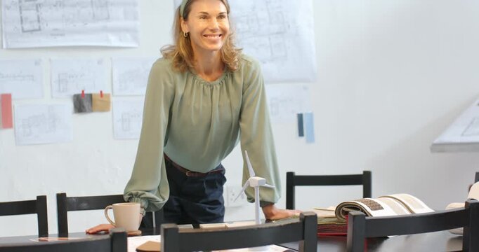 After review mid adult woman wearing green top explaining design presenting turbine model in studio