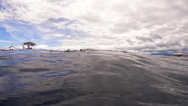 Low angle view of floating debris and plastic waste on the ocean surface near a Bangka boat with adult men, Philippines.
