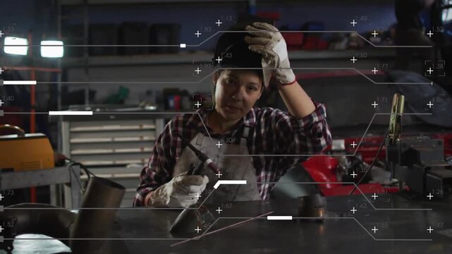 Woman welder finishing weld at bench lifting helmet checking weld while HUD marking joint