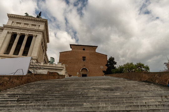 Stairs and facade of the Santa Maria in Aracoeli Basilica in Rome, with the side view of the Monument on the side in springtime, Rome, Italy