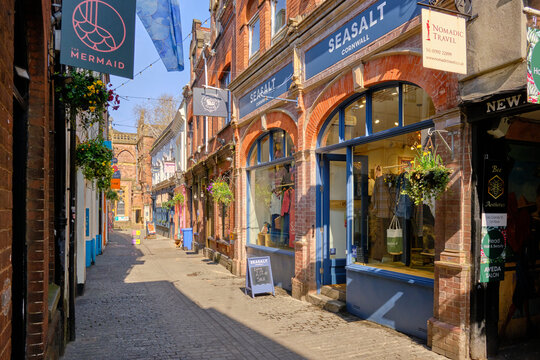 Exeter, United Kingdom  - March 22 2026. Gandy Street's eclectic independent shops with vivid blue facades, flower-filled hanging baskets and bunting bring colour and character.