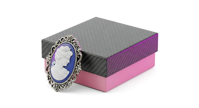 Antique cameo brooch with intricate silver filigree, resting on a decorative gift box with pink and gray textured lid, elegant accessory