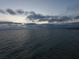 Fototapeta premium Ocean waters under cloudy sky at dusk with horizon view