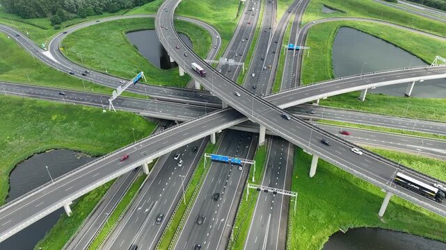 Aerial drone view of a multi-level highway intersection with moving cars near the city of Rotterdam, The Netherlands. Trucks move along a multi-level road junction. The concept of the urban.