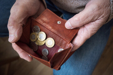 Starszy mężczyzna liczy drobne monety z portfela. © Blaszko
