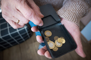 Starszy mężczyzna liczy drobne monety z portfela. © Blaszko