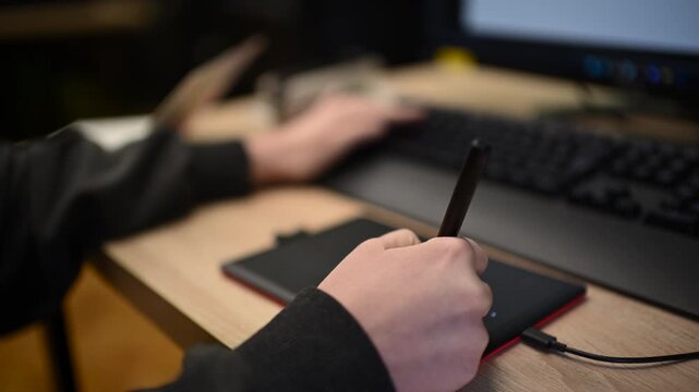 Person using graphic tablet connected to computer for digital design work