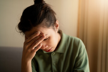 Fototapeta premium A close-up image of a young woman touching her forehead. She looks stressed and anxious.