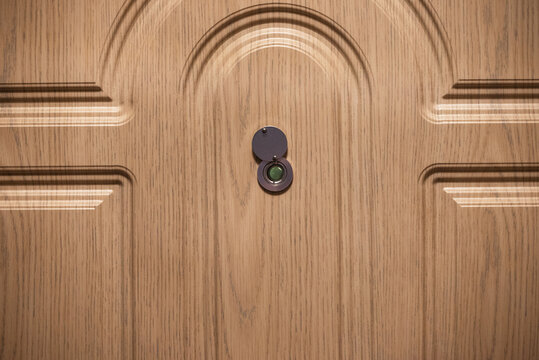 Open peephole on wooden door close up