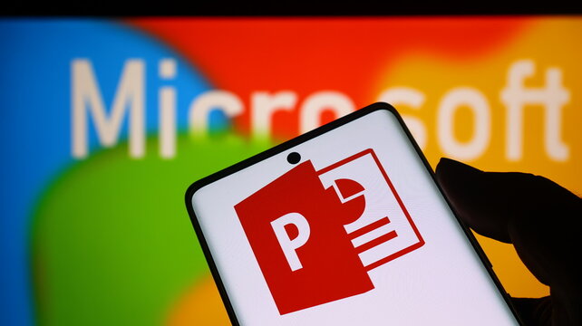A hand holding a smartphone with the Microsoft PowerPoint logo on the screen