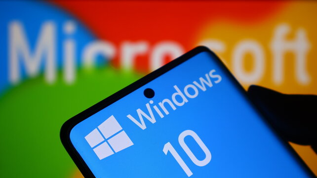 A smartphone displaying the Windows 10 operating system in front of a Microsoft logo background.