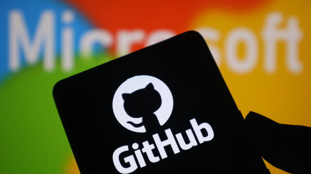 A smartphone displays the GitHub logo in front of a blurred Microsoft background