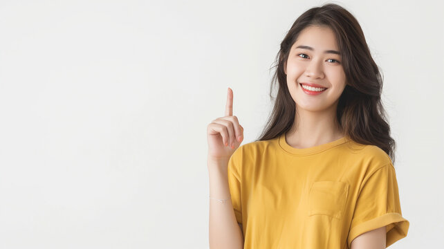 Smiling young Asian woman pointing up at copy space isolated on white background