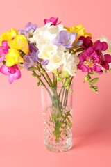 Fototapeta premium Beautiful freesia flowers in vase on pink background, closeup