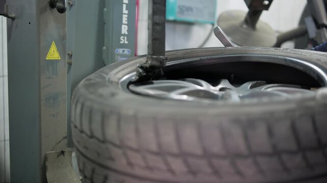 Professional mechanic removing a tire from a wheel using a special machine in an auto repair shop. Close up shot of the tire changer machine during the tire mounting and demounting process