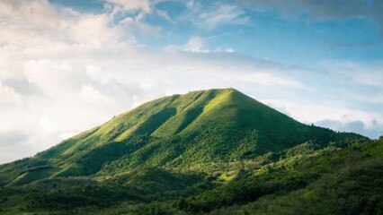Obraz premium Lush green hill rises under soft blue sky