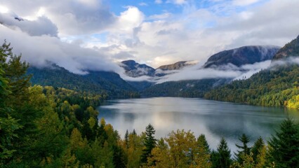 Fototapeta premium Misty mountains loom above calm lake waters