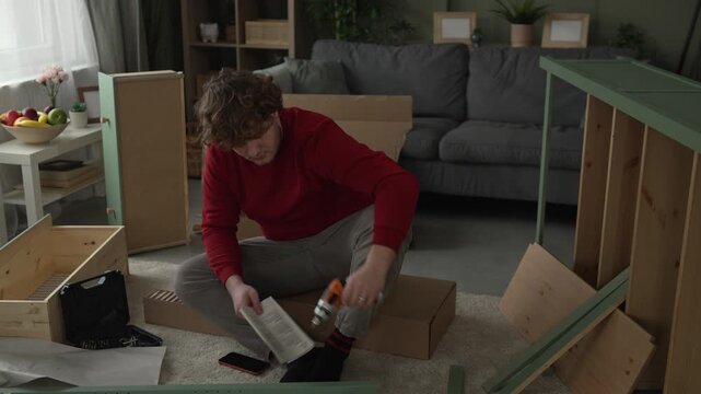 Frustrated man trying to assemble furniture following instructions